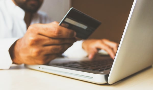 Hombre con tarjeta de crédito y ordenador portátil haciendo una compra online